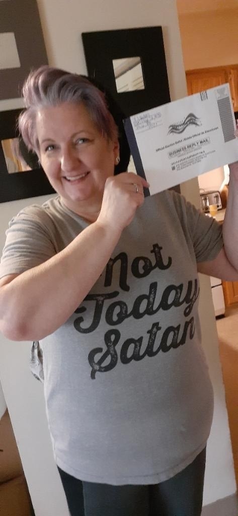 Image of Vicki Landers wearing a &quot;Not Today Satan&quot; t-shirt. She has grey purple hair and is holding her ballot next to her face