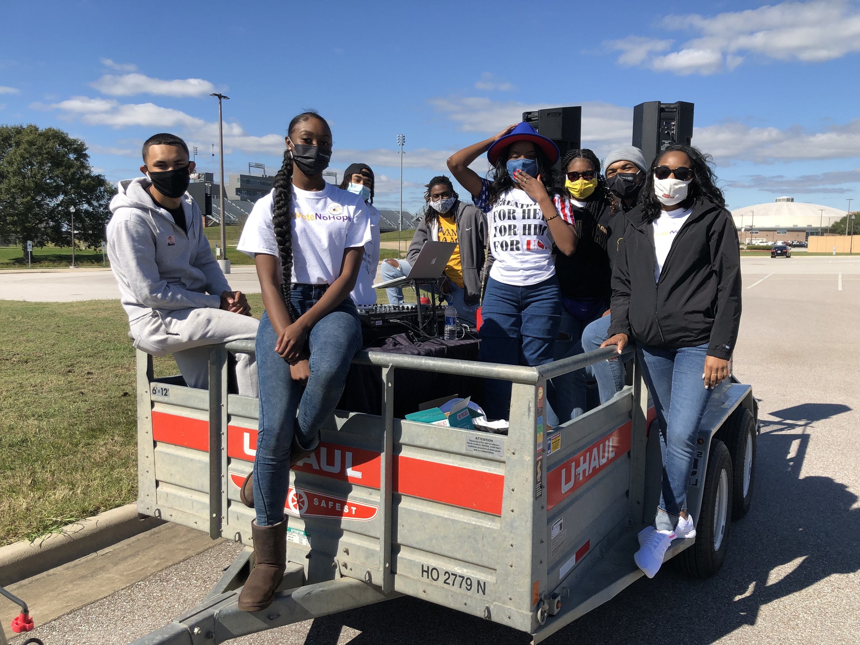 Students wearing masks stand in a U-Haul trailer