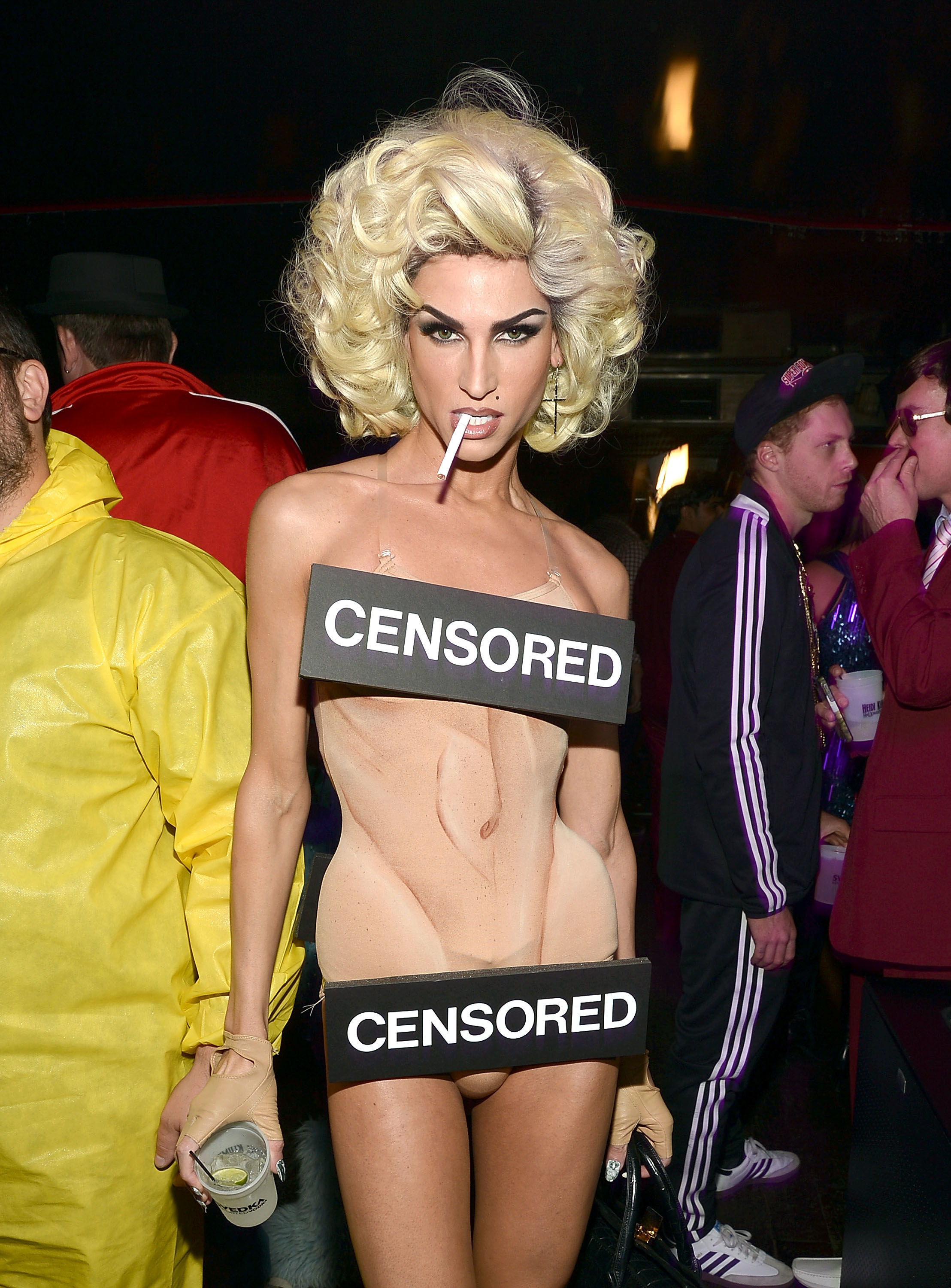 Man who appears naked with make-up and censored bars at a Halloween party. 