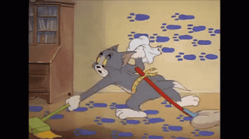 A GIF of Tom from &#x27;Tom and Jerry&#x27; cleaning footprints with a mop in his hand and a mop tied to his waist.