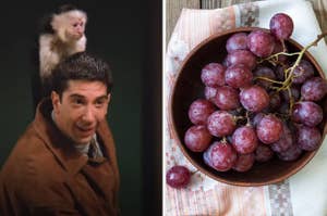 A man is holding a monkey on his shoulder with a bowl of grapes on the right