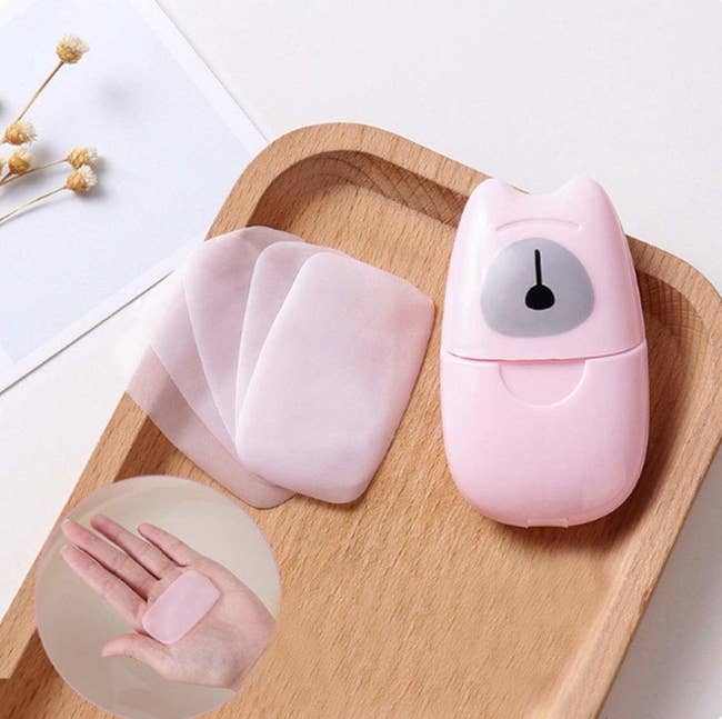 The pink plastic container with ears and a nose, plus the pink paper-thin soap sheets