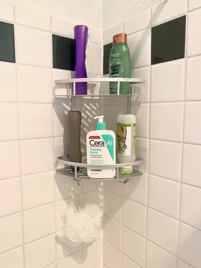Reviewer photo of the silver shelf holding toiletries and a loofah