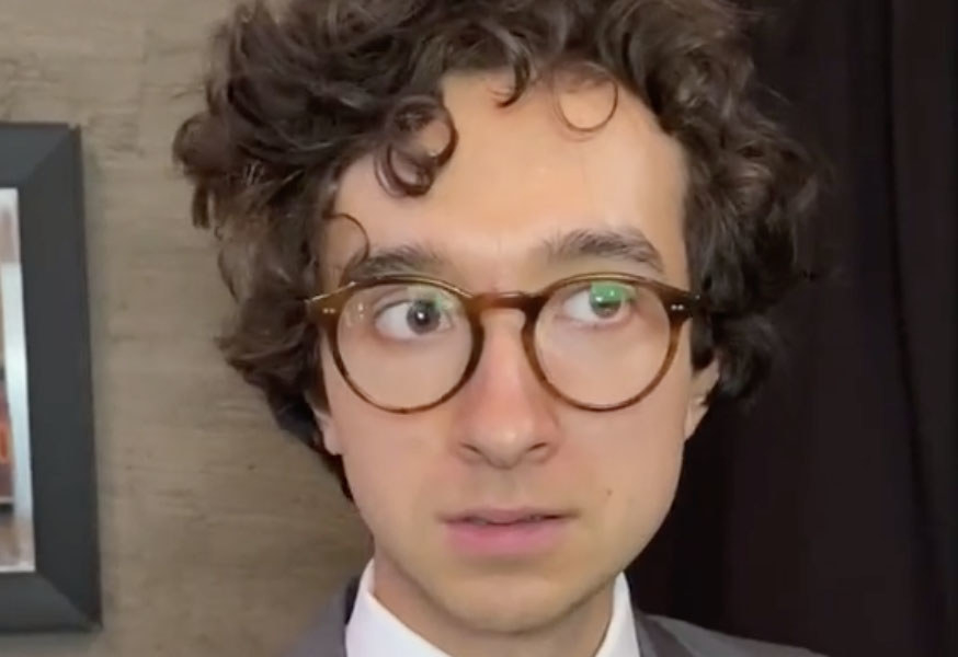 A man wearing a suit and glasses looks concerned