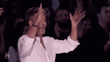 An animated GIF of Simon Cowell signing &quot;applause&quot; in ASL