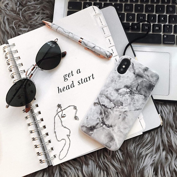 An iPhone placed on an open agenda next to a laptop