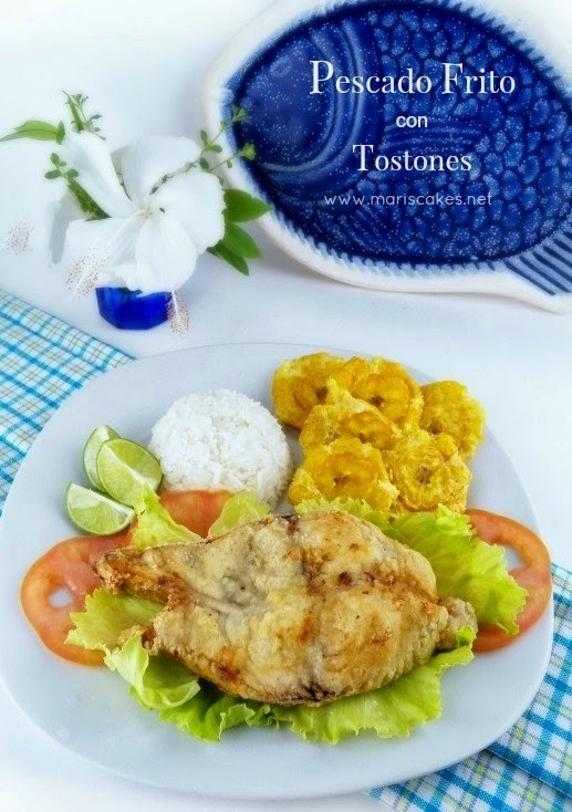 A plate of pescado frito served with rice, plantains, and tomatoes.