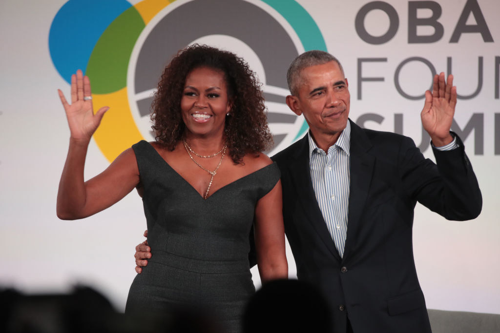 Michelle and Barack smiling with their hands raised