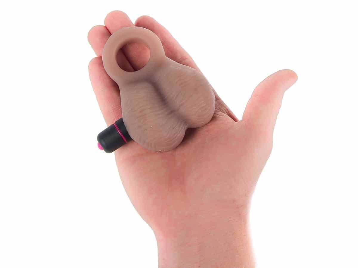 a hand holding the love bump which has a stretchy ring for wear and a bullet vibe inserted into the toy 