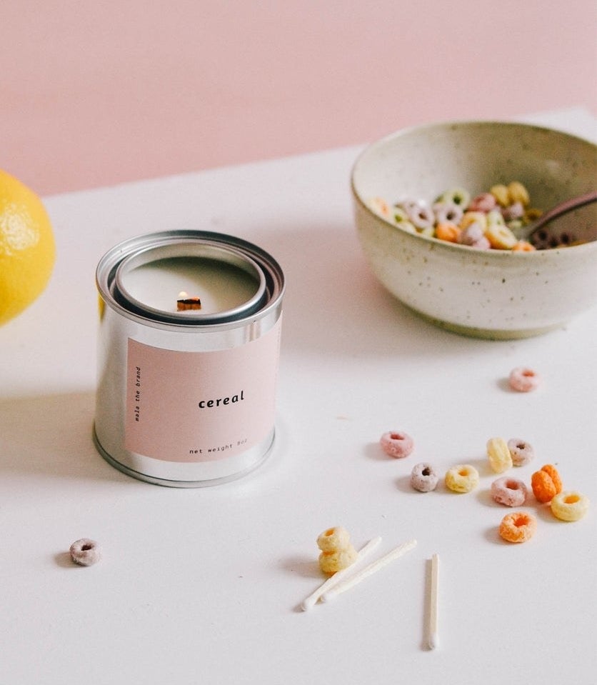 The candle on a table with a bowl of cereal next to it