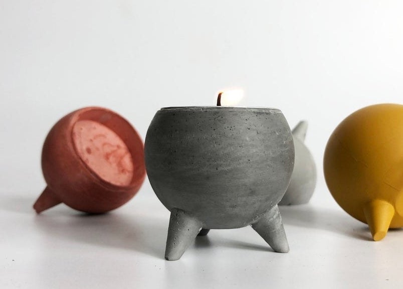 Four tea light holders on a table, one has a candle inside