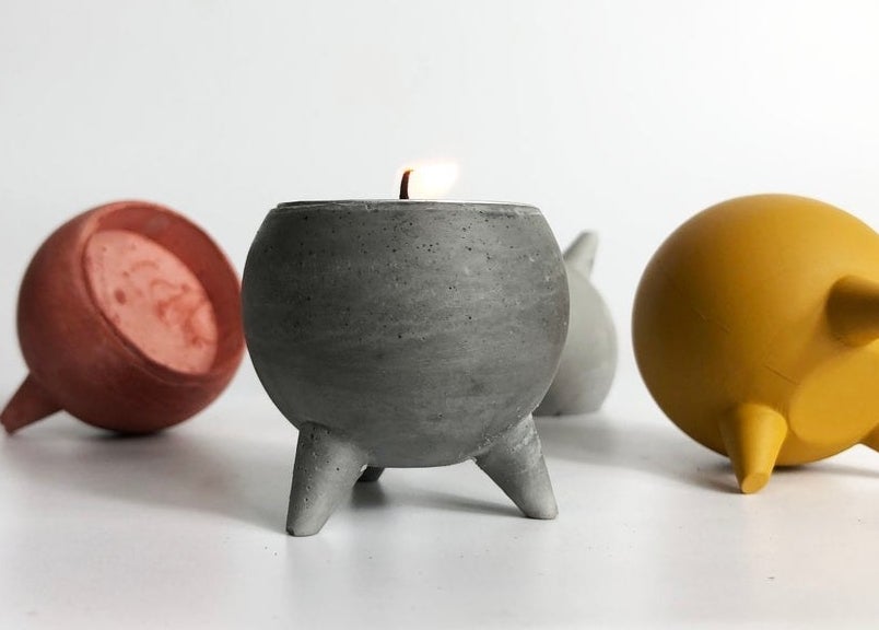 Four tea light holders on a table, one has a candle inside