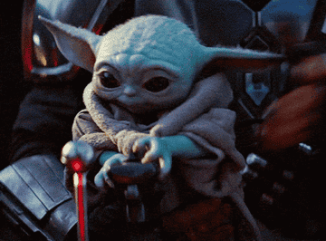Baby Yoda trying to press a lever on a space ship 