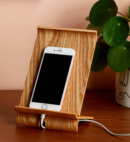 The curved wooden mount holding a cell phone on a desk