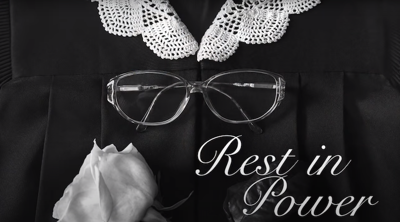 RBG&#x27;s Supreme Court robe, collar, and glasses with a rose and text saying &quot;Rest in Power&quot;