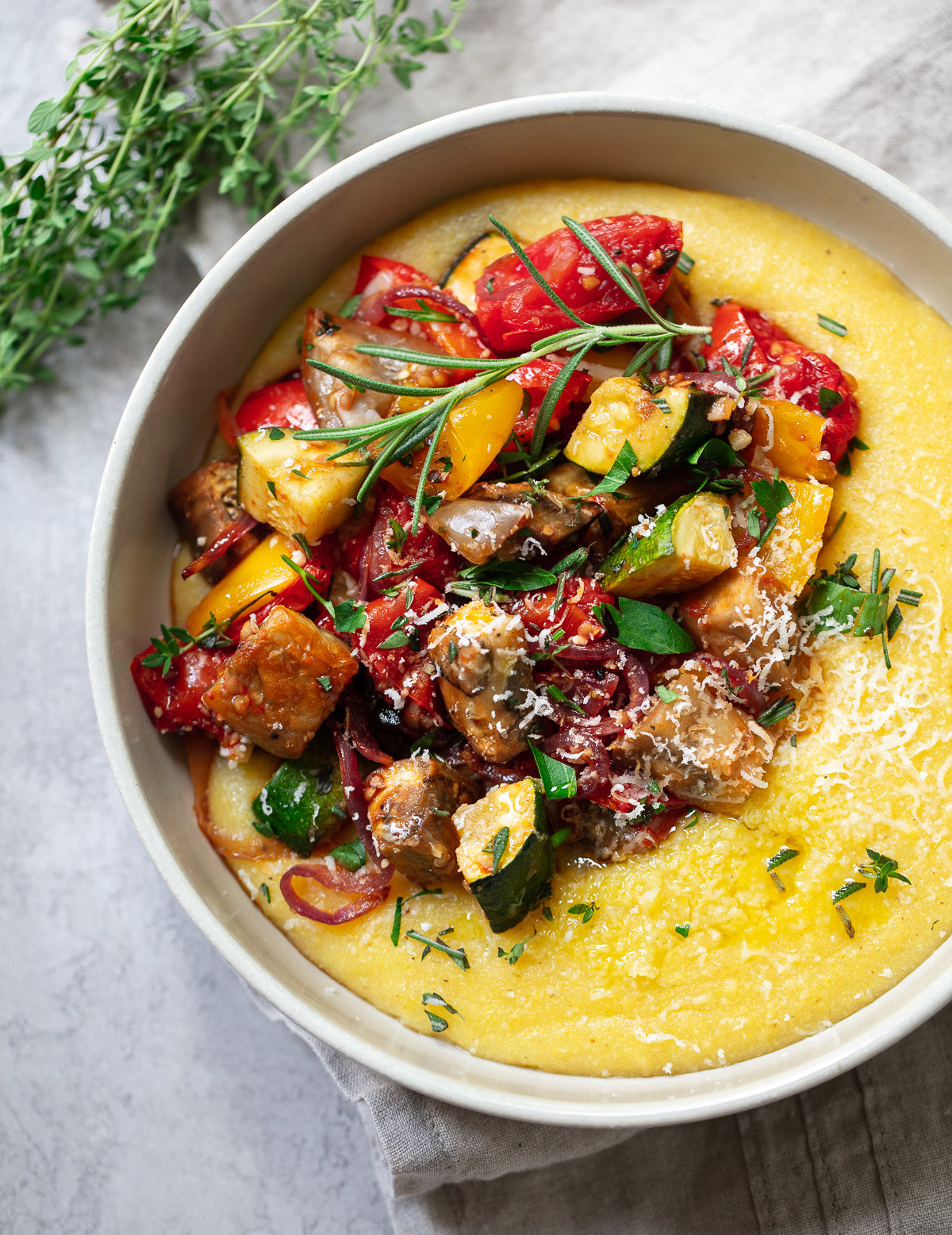 A bowl of cheesy polenta topped with diced roasted vegetables
