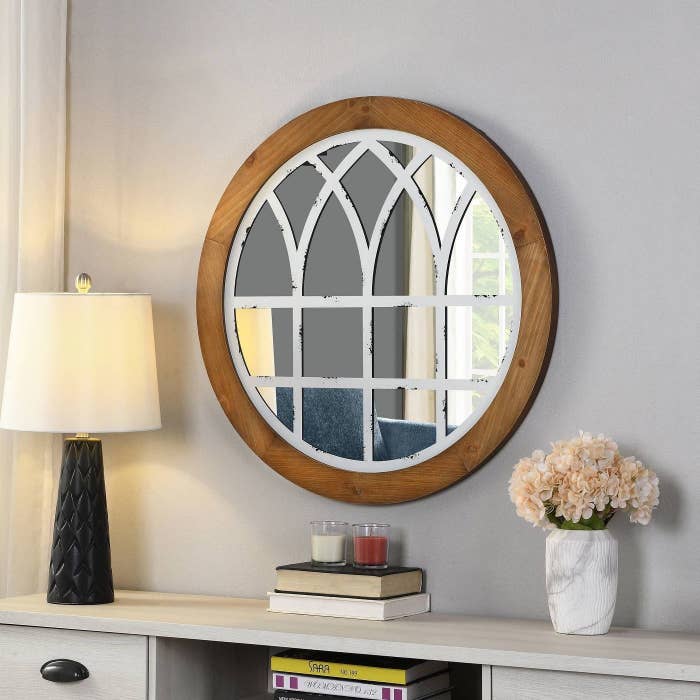 wooden framed circular mirror with white rustic design on top