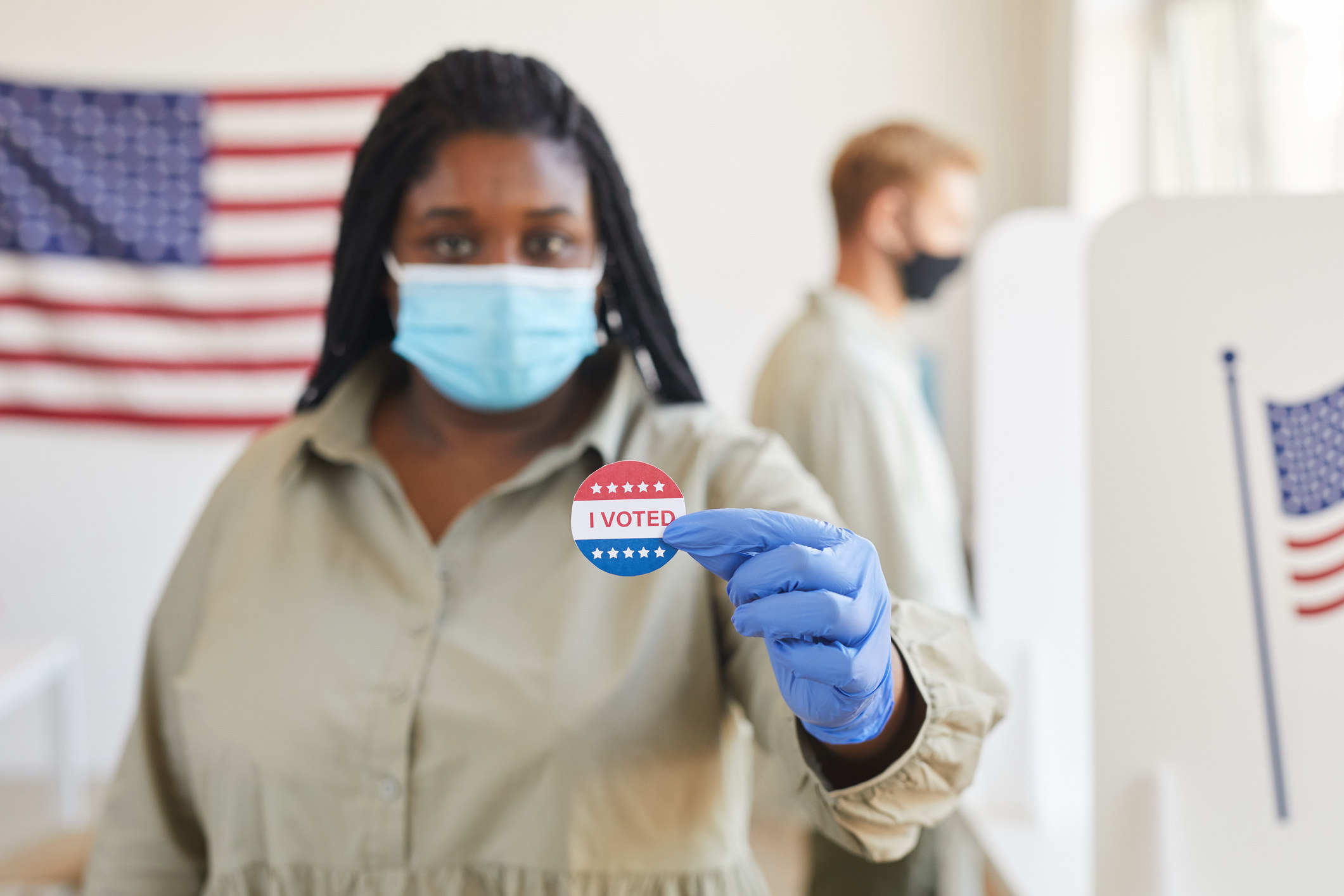 A woman holding up an "I voted" sticker