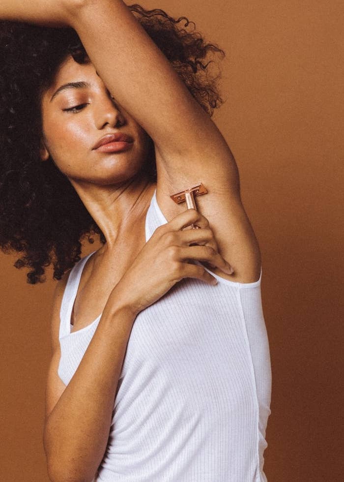 Model using the rose gold-colored razor on their armpit