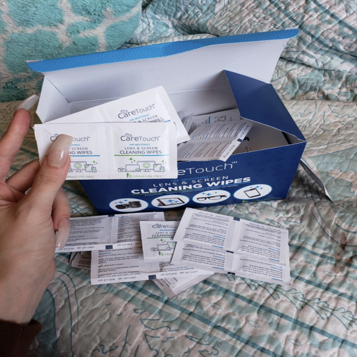 A reviewer pulling out some of the individually wrapped wipes out of the box