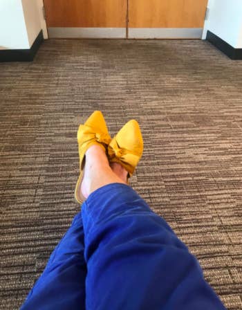 Reviewer wears yellow bow mules with blue skinny pants