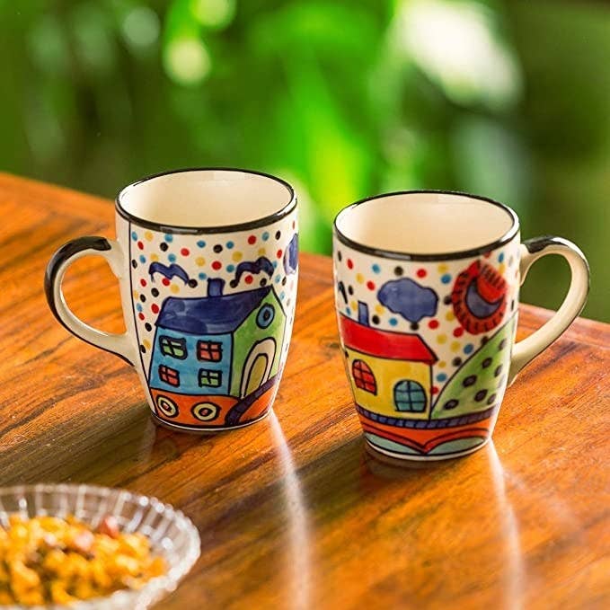 Hand painted ceramic mugs with house drawings on them.
