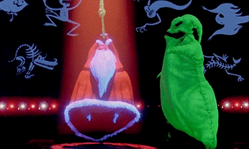 Santa is hung up by his hands above him as Oogie Boogie sings