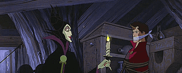 Maleficent holding a candle up to Philip, who is tied up and gagged