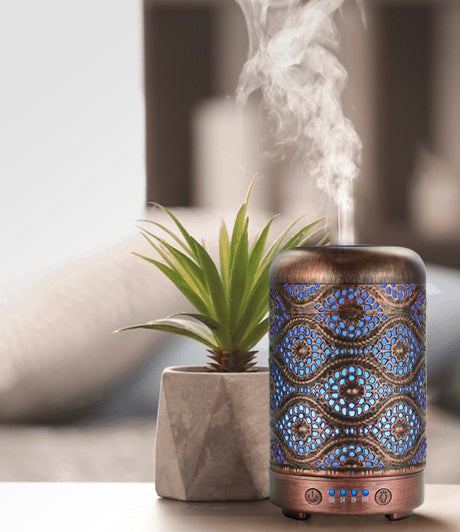 An essential oil diffuser with a pretty hammered pattern on a table