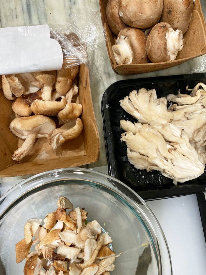 An assortment of different mushrooms, with some mushrooms chopped in a mixing bowl.