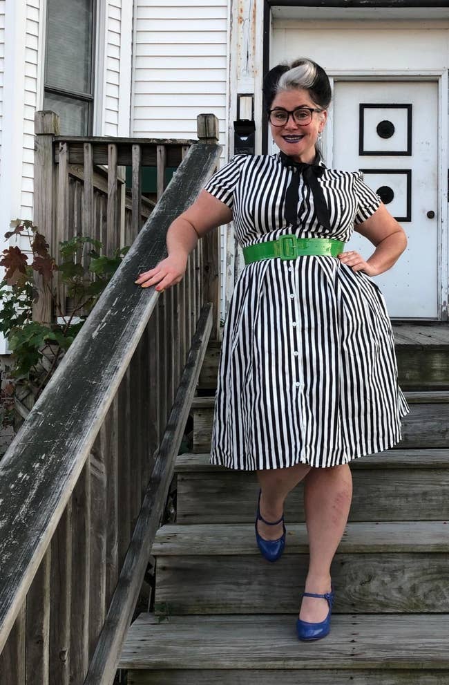 Reviewer wearing the knee-length short-sleeved dress with black and white vertical stripes all over it