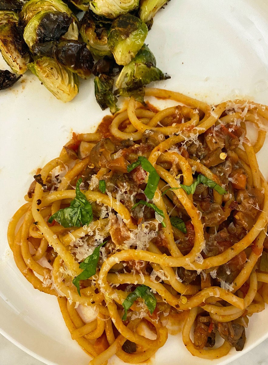 Pasta in mushroom "Bolognese" sauce, plated with basil and Parmesan and a side of Brussels sprouts.