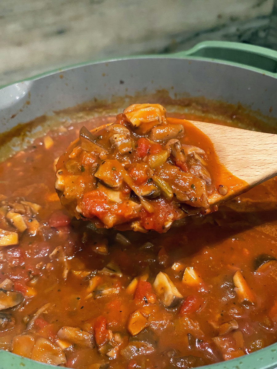 A wooden spoon holding a scoop of the mushroom Bolognese sauce.