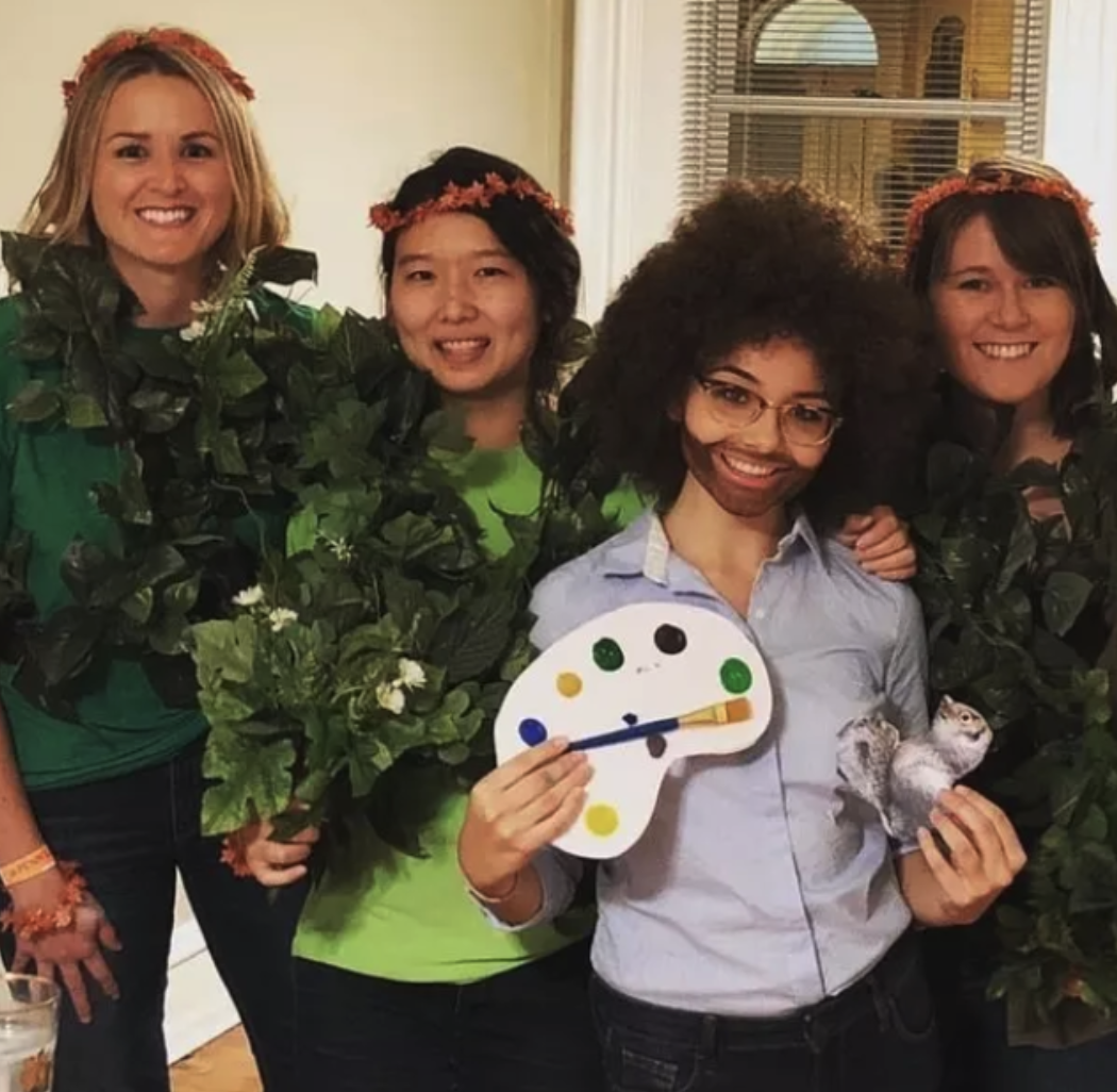 A group of friends dressed as painter Bob Ross and some green trees