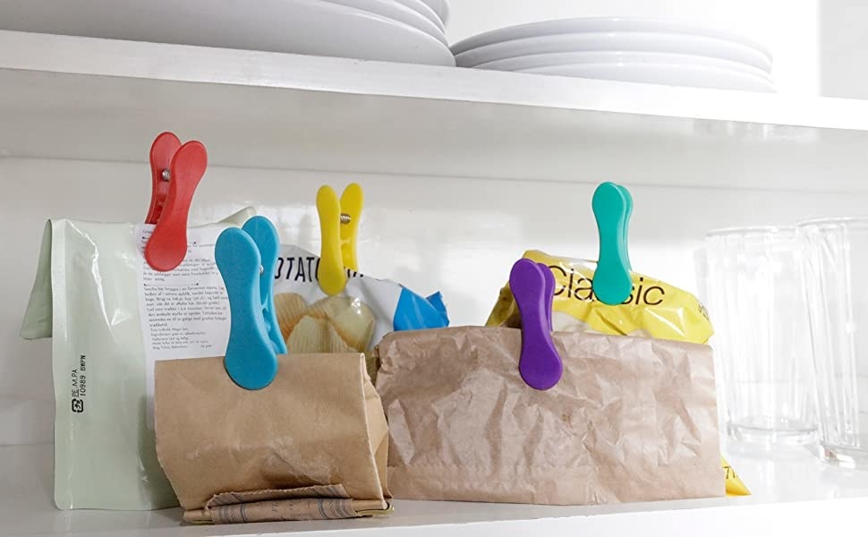 Five rainbow clips securing bags shut on a kitchen shelf