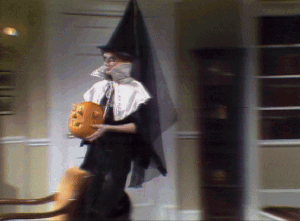 a gif of the conehead daughter removing her witches hat and holding a pumpkin