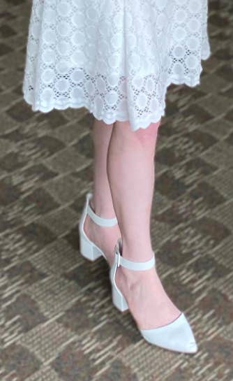 Reviewer wears the low-heel ankle-strap pump in a white shade with a white embroidered dress