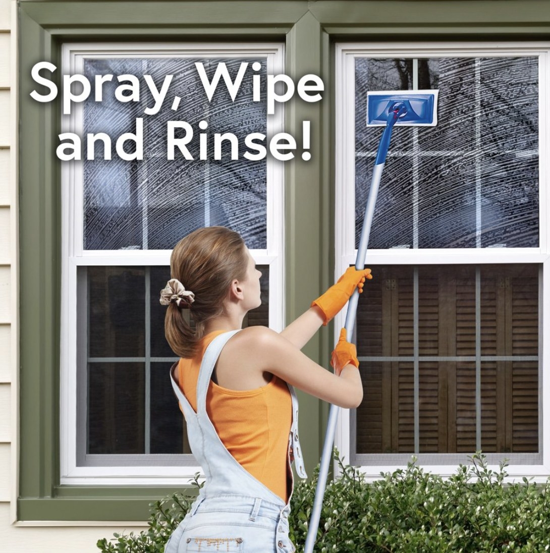 Model is outside of a home wiping windows clean with an expandable cleaning tool