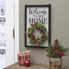 A sign that says "Welcome to our Home" with a hanging holiday/Christmas wreath