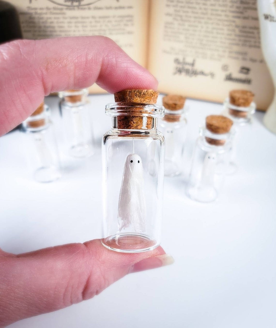 little ghost hanging in small glass jar with cork stopper 