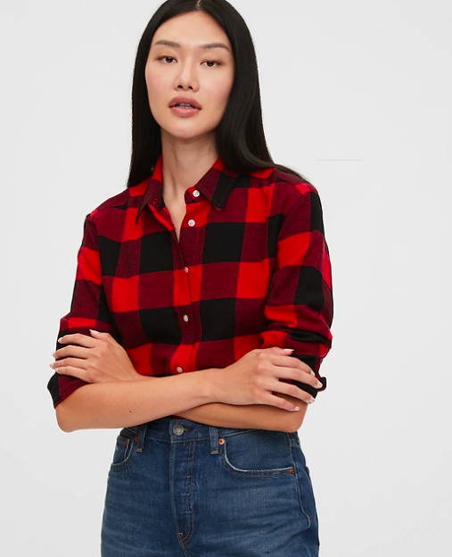 A model with arms crossed wearing the flannel shirt with a pair of denim