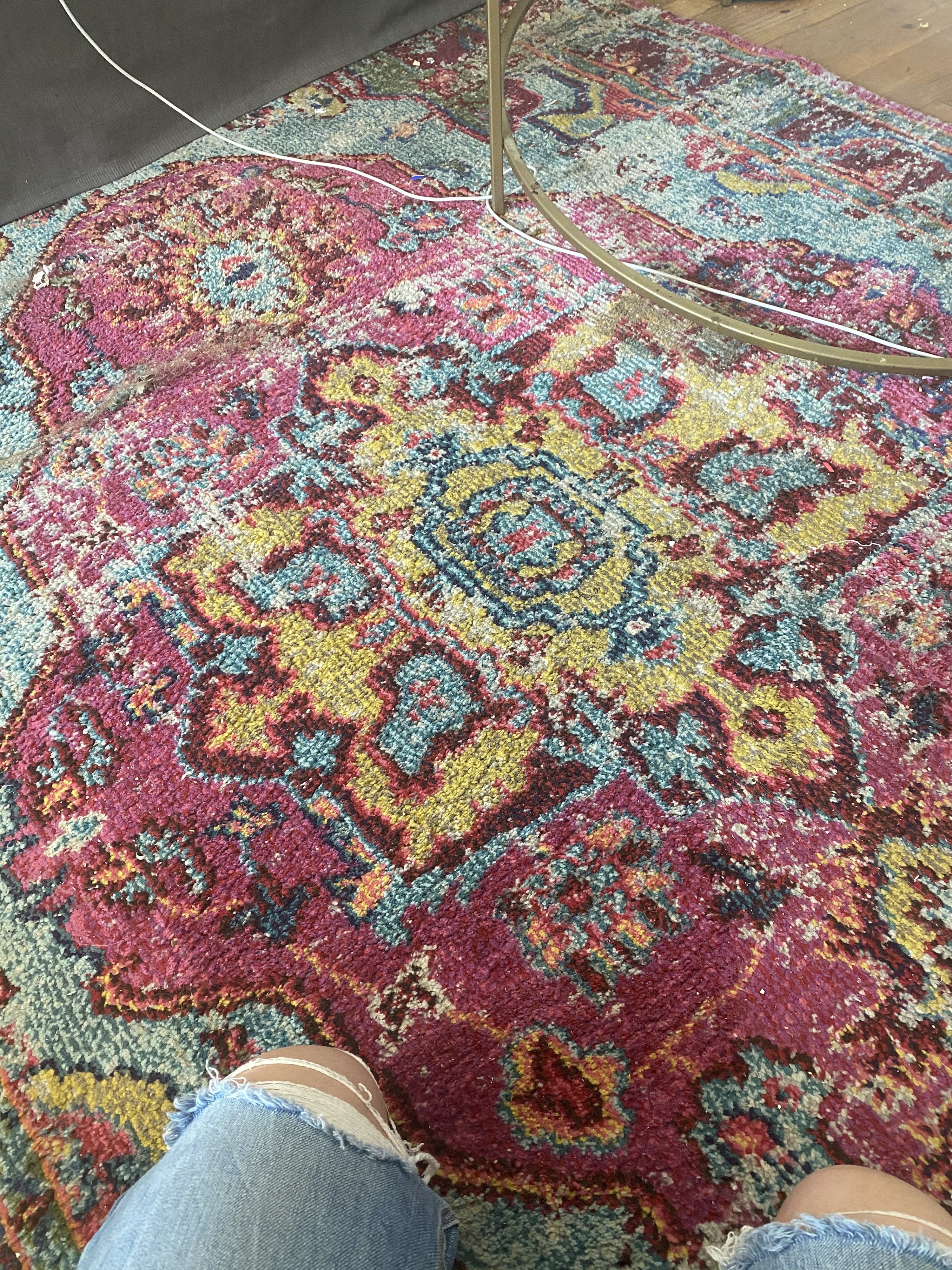 A pink and yellow and blue carpet on a hardwood floor 