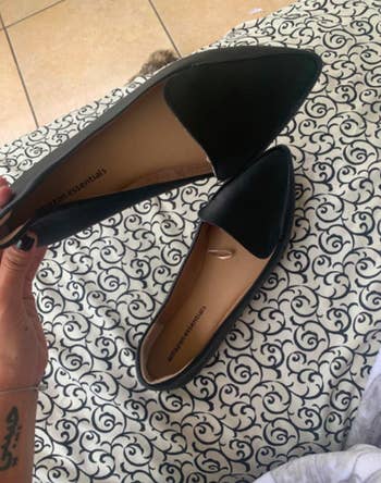 Reviewer holds up same style shoe in a black shade with their hand