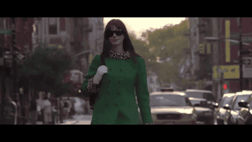 Andy Sachs from &quot;The Devil Wears Prada&quot; walking in a green coat and gloves and trying to not slip in their shoes