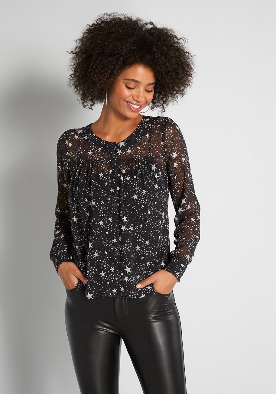 model wearing black top with white stars and sheer sleeves