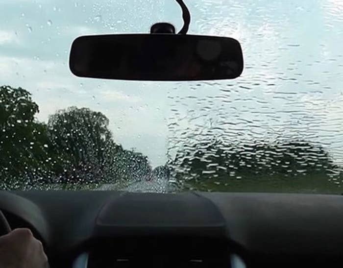 Person's windshield with one half that's clear and one that's blurred from rain