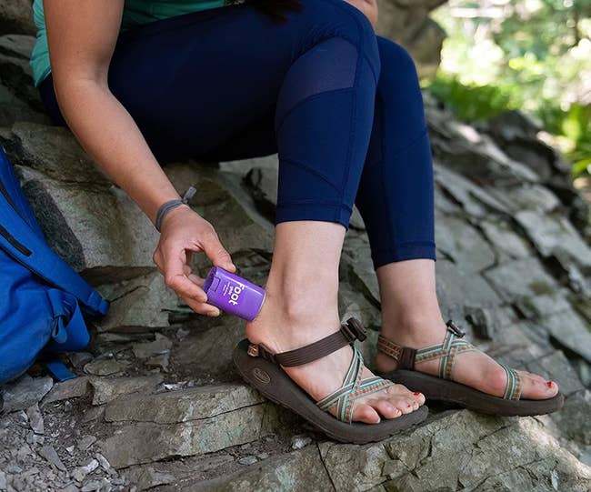 A model applies the BodyGlide Foot Anti Blister Balm to the back of their ankle