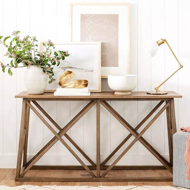 A console table with art frames, a plant, and this gold round sculpture