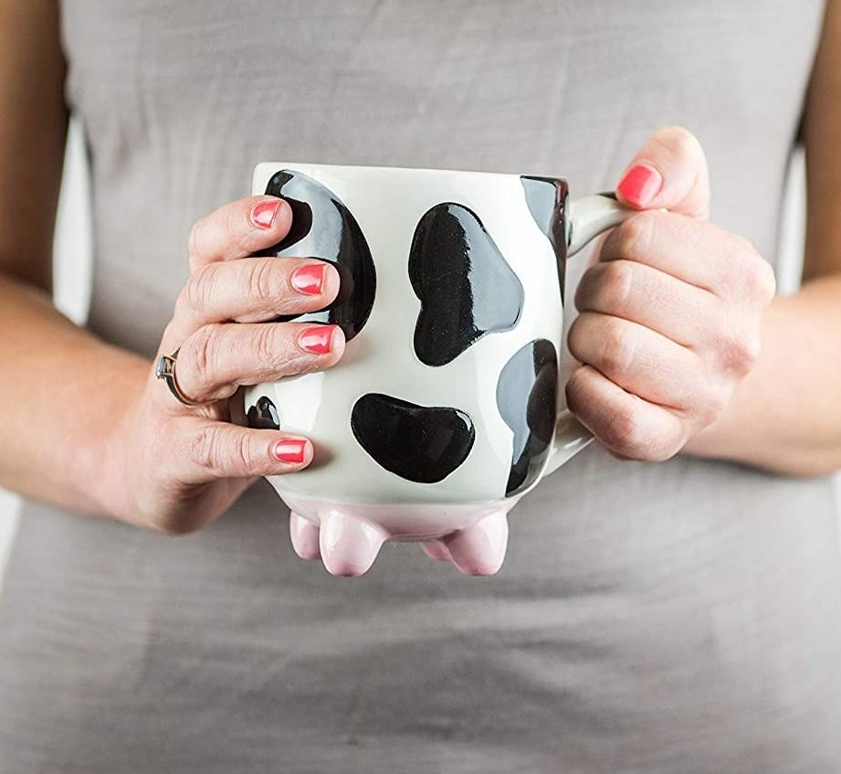 A person holding the cow-shaped mug