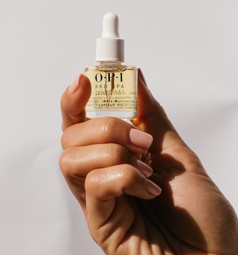 A person holding a bottle of cuticle oil